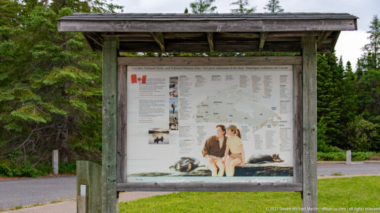 Timber-roofed outdoor kiosk displaying a map of Canada's national parks and national historic sites.