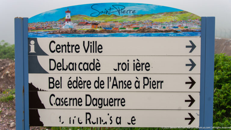 Saint-Pierre directional sign with a harbor panorama, arrows, “Centre Ville,” “Caserne Daguerre,” and other destination names.