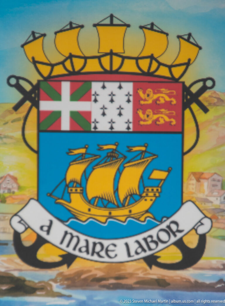 Saint-Pierre-et-Miquelon coat of arms with a sailing ship, three upper banners, and the motto “A Mare Labor.”