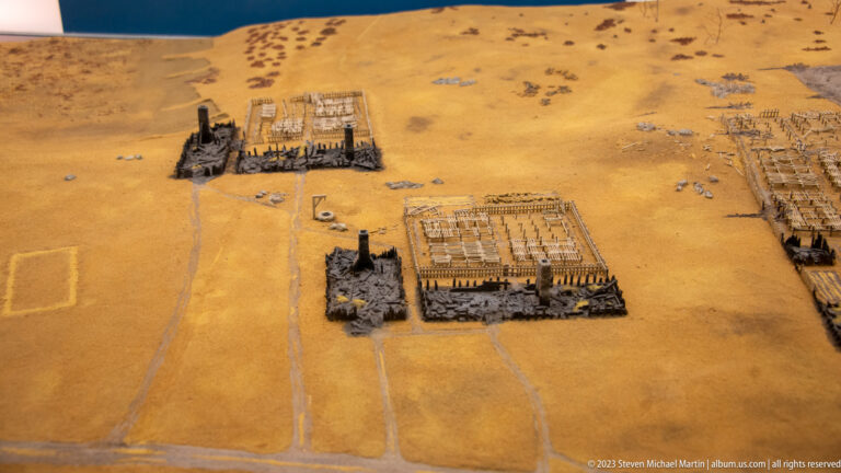 Scale model showing scattered building compounds and roads across a sandy historic landscape.