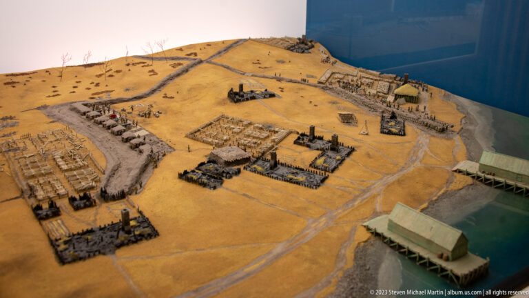 Oblique scale-model view of Louisbourg settlement extending toward a blue waterfront edge.
