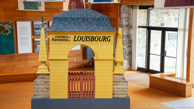 Yellow scale model of a gated fortress entrance labeled Fortress/Forteresse Louisbourg in the visitor centre.