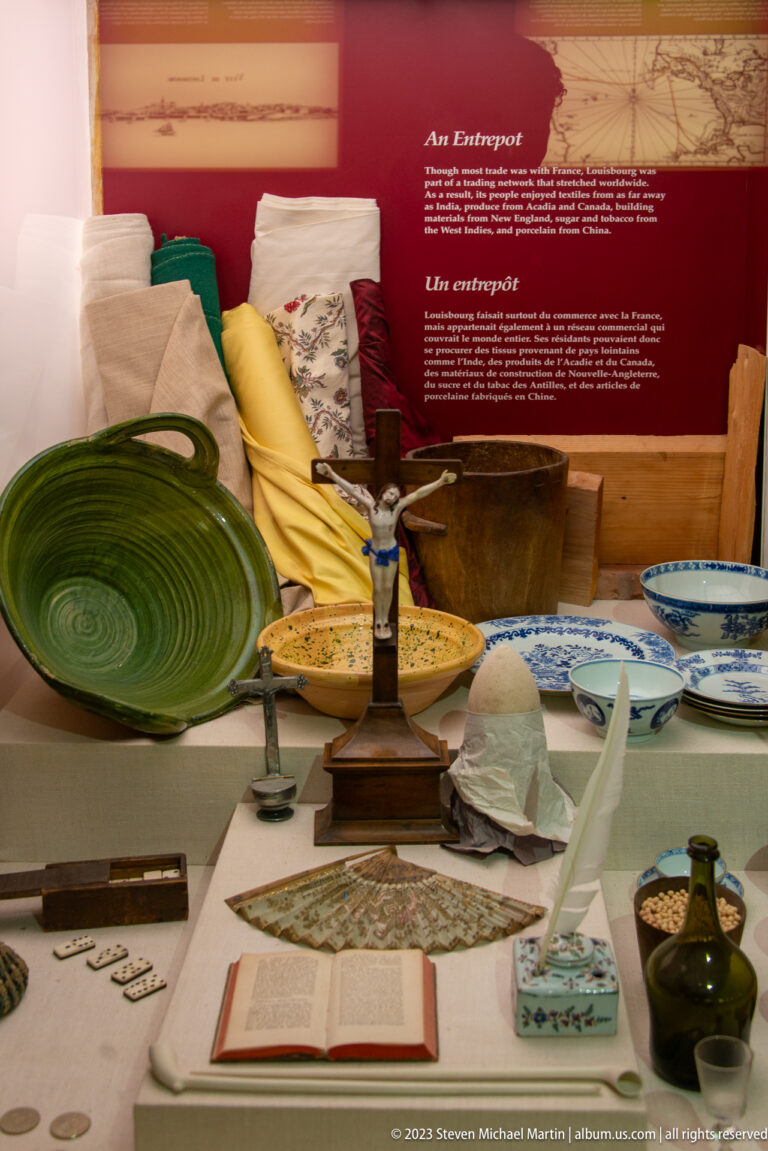 Museum case with ceramics, textiles, books, tableware, and small eighteenth-century objects.