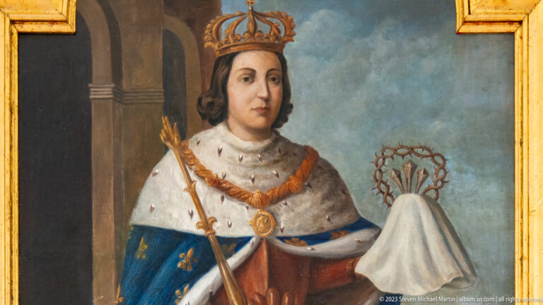 Painted crowned ruler in blue fleur-de-lis robe and ermine mantle holding royal regalia.