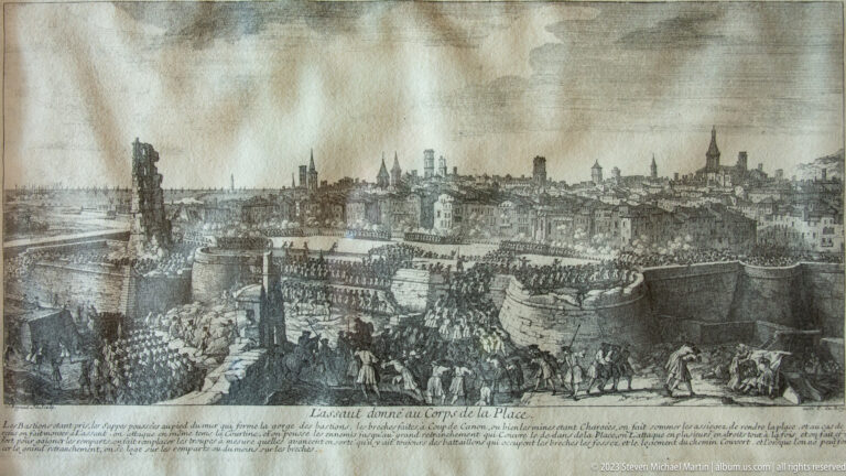 Historic engraving showing a fortified town, defensive walls, troop formations, and siege works around Louisbourg.