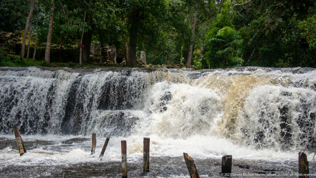 White water rushes over a broad dark ledge in multiple heavy curtains.