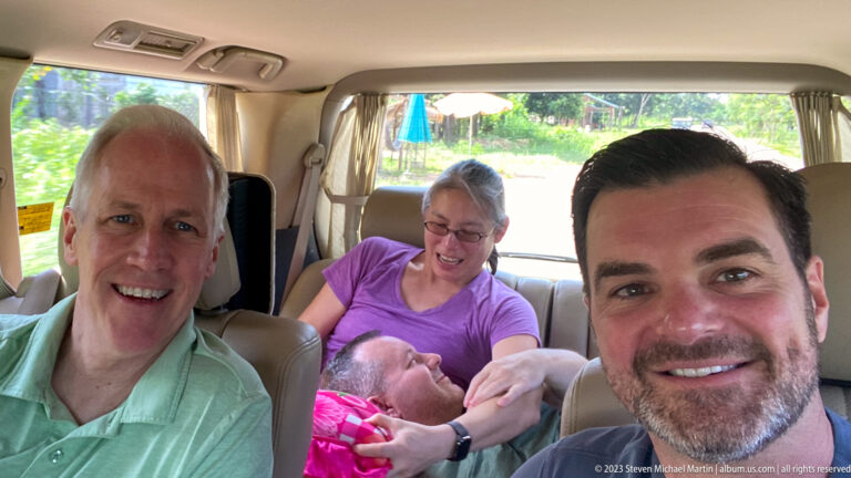 Four travelers pose for a cheerful selfie inside a van after an excursion.