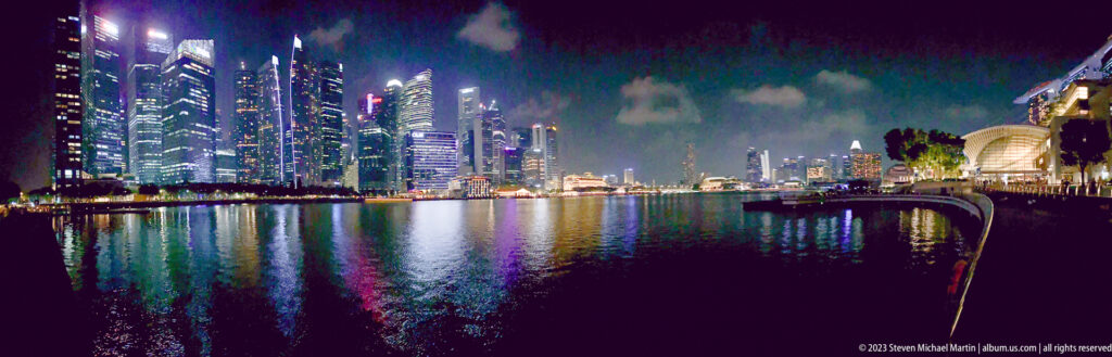 Wide-angle nighttime view of Singapore’s skyline and colorful reflections across Marina Bay.