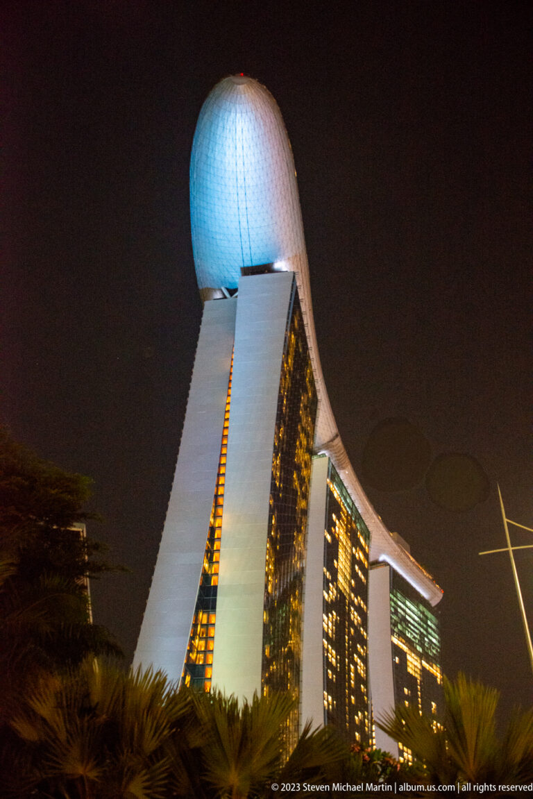 End-on nighttime view of a Marina Bay Sands tower with the rounded SkyPark projecting above.