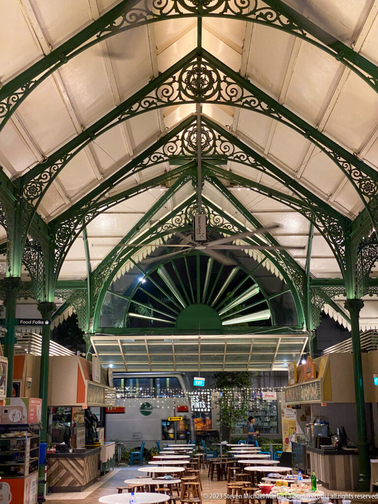Symmetrical Lau Pa Sat roof with green iron trusses and a large radial fanlight.
