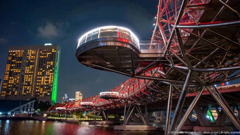 Rounded viewing pod extending from the red-lit steel lattice of the Helix Bridge.