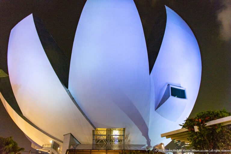 Near-frontal nighttime view of the white ArtScience Museum with a dark central opening.