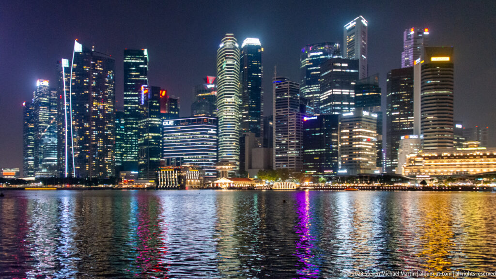 Illuminated downtown Singapore skyscrapers reflected in Marina Bay at night.