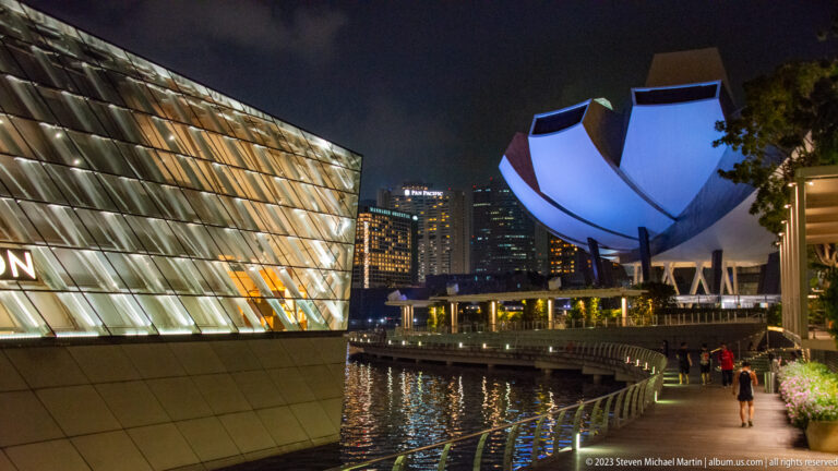 Faceted Louis Vuitton pavilion beside the white ArtScience Museum along Marina Bay at night.