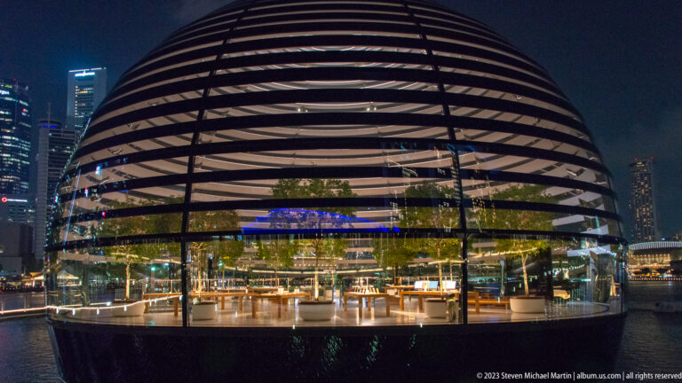 Close frontal view of the banded spherical Apple pavilion with glass walls and interior planting.