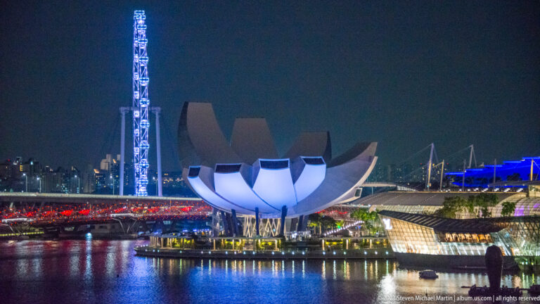 ArtScience Museum at night with the Singapore Flyer and illuminated waterfront structures behind it.