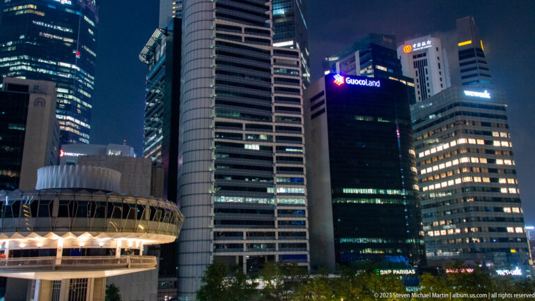 Supreme Court roof at lower left beneath illuminated office towers in central Singapore.