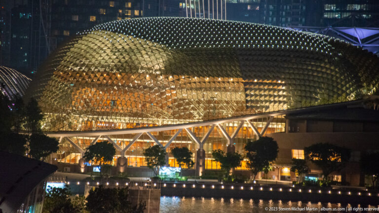 Close nighttime view of an Esplanade dome covered in triangular sunshades above a lit lower façade.