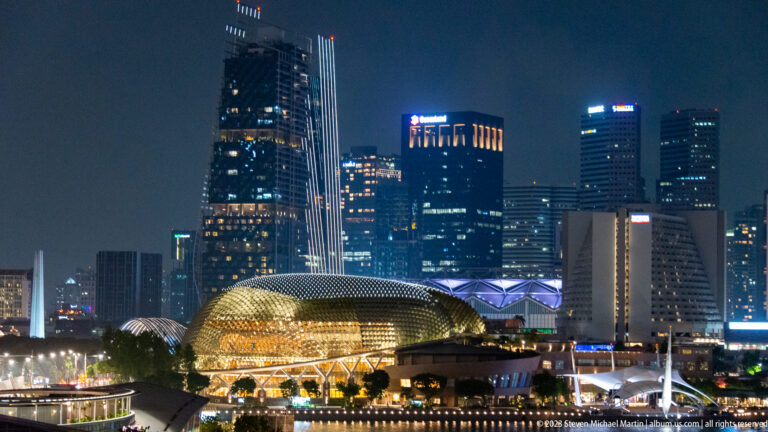 Golden Esplanade domes beside the waterfront with tall Singapore buildings rising behind.