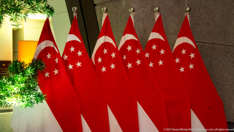 Cluster of Singapore flags with white crescents and stars displayed indoors.