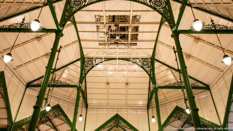 Upward view of green decorative cast-iron columns and roof trusses inside Lau Pa Sat.