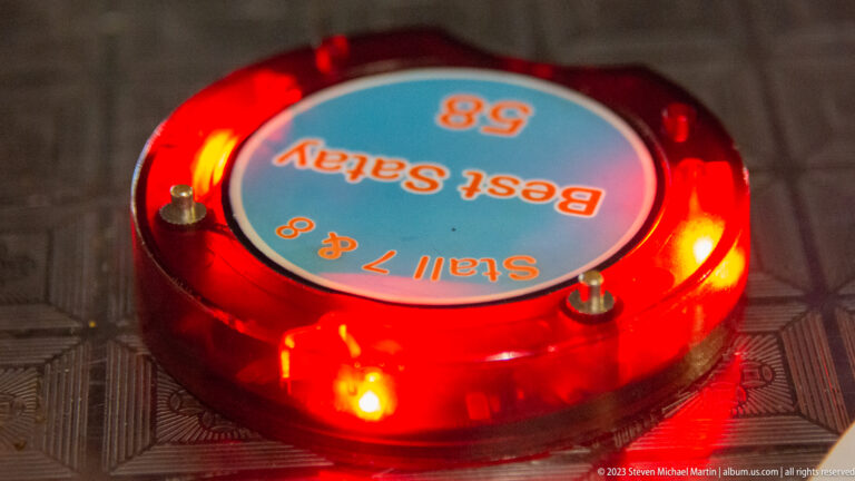 Red illuminated restaurant pager labeled Stall 7 and 8, Best Satay 8.