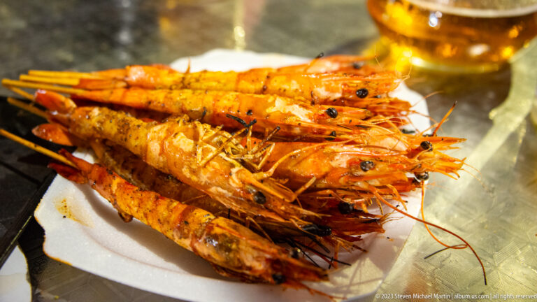 Plate piled with grilled whole prawns showing charred shells and intact heads.