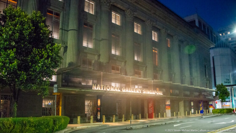 National Gallery Singapore at night with illuminated stone façade and entrance signage.