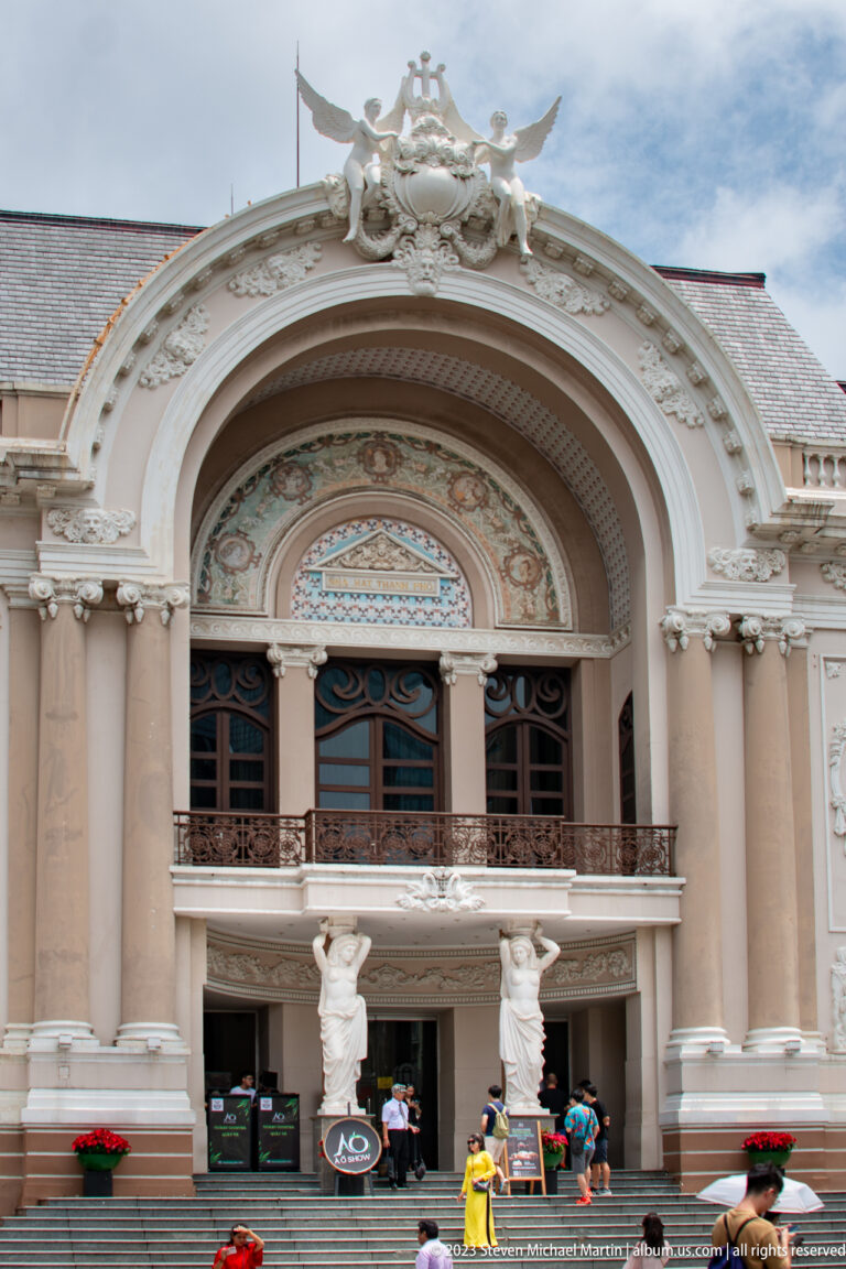Close view of the Saigon Opera House entrance with columns, sculpture, and painted ornament.