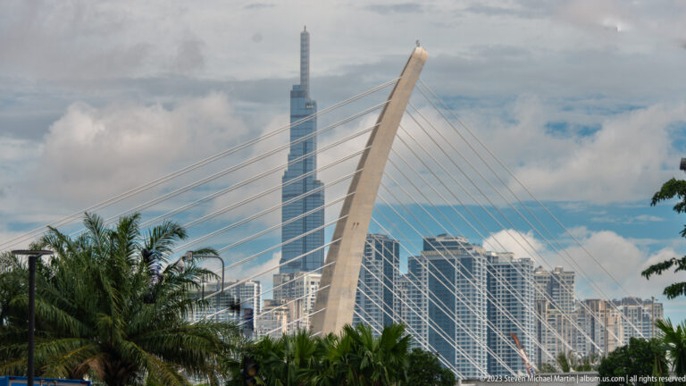 Cable-stayed bridge cables crossing a skyline dominated by Landmark 81.