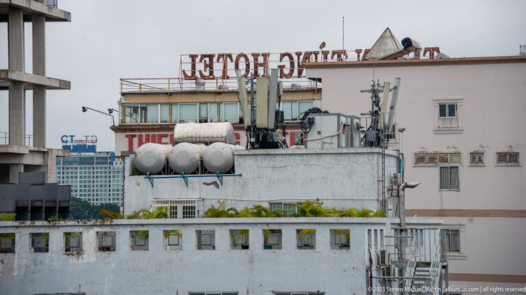 White rooftop crowded with water tanks, antennas, pipes, and reversed hotel signage.