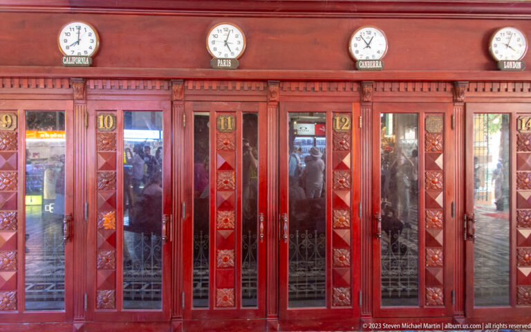 Red wooden telephone booths with numbered doors and world clocks for Paris, Canberra, and London inside the post office.