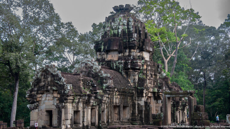 Weathered sanctuary tower rising above dense tropical trees at Angkor Thom.