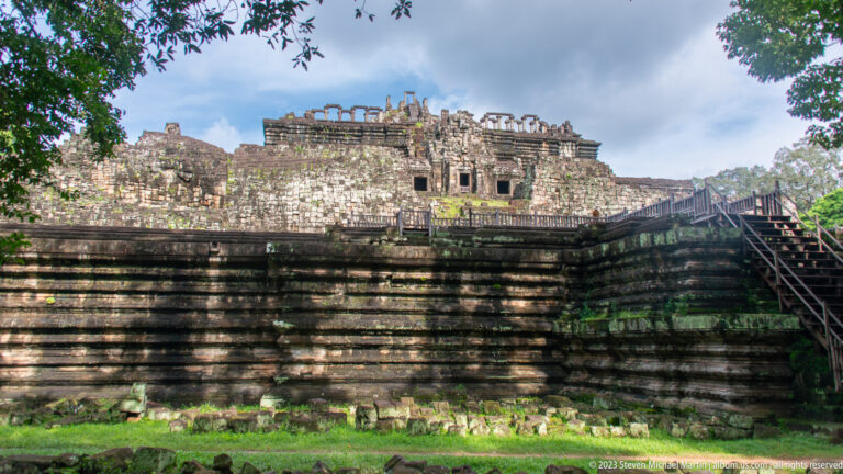 Long weathered wall with pale upper terrace and central opening at Angkor Thom.
