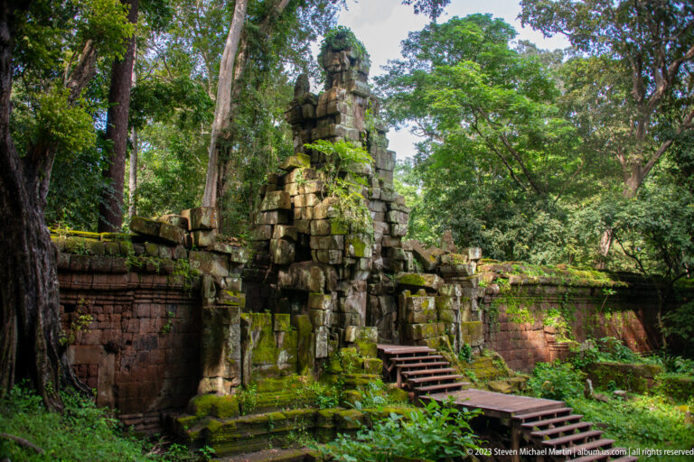Small stone gateway among trees and collapsed masonry at Angkor Thom.