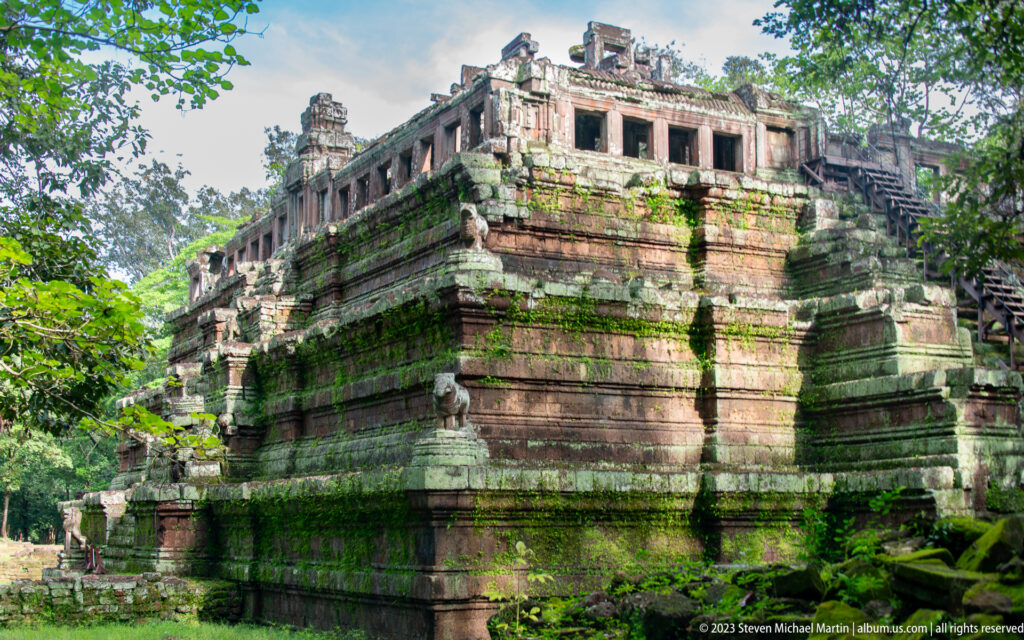 Large rectangular stepped pyramid covered in moss at Angkor Thom.