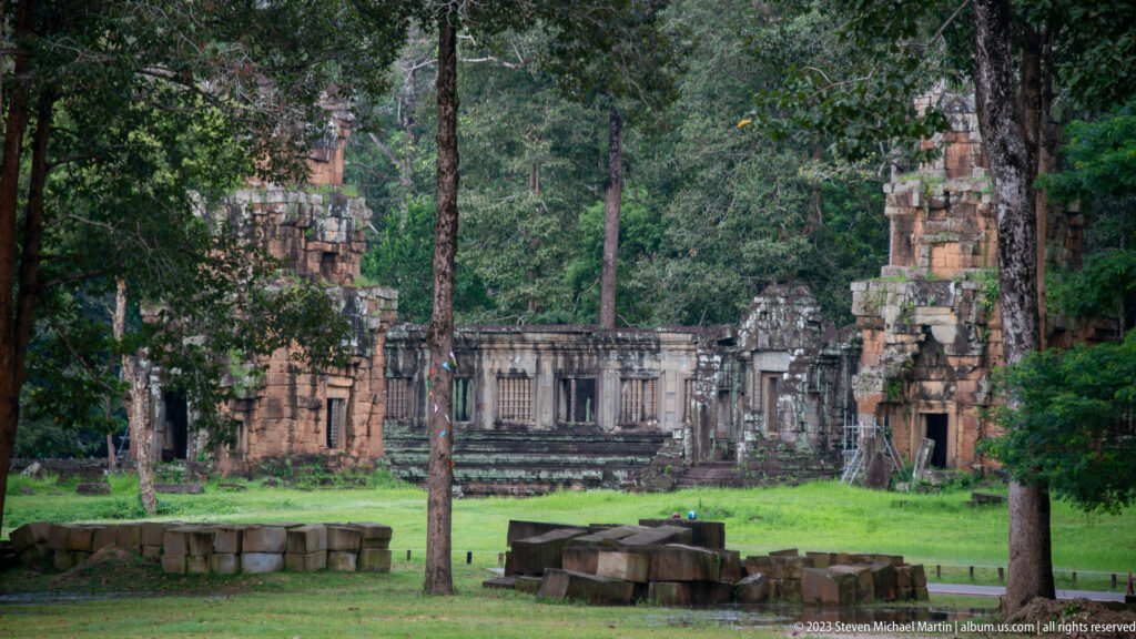 Distant ruined temple façade across a grassy clearing at Angkor Thom.