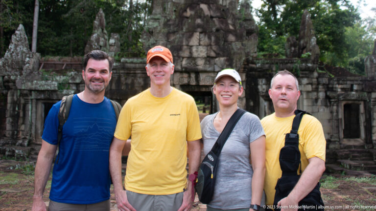 Four visitors posing together before the temple entrance at Angkor Thom.