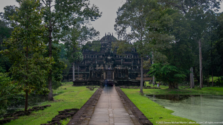 Long straight causeway approaching a large stepped temple at Angkor Thom.