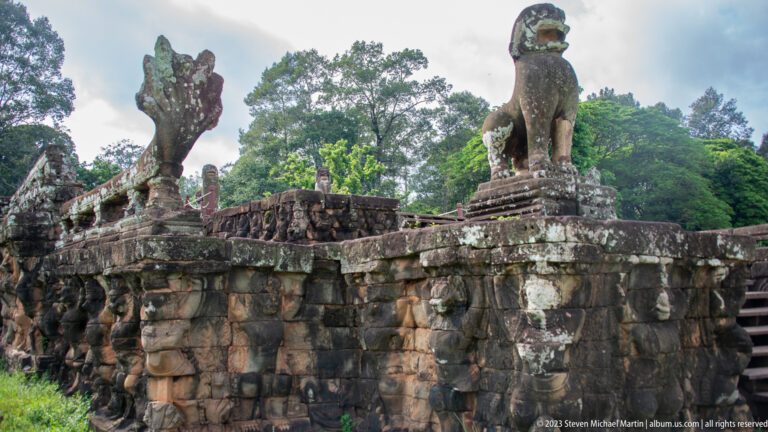Stone guardian lions standing atop a terrace wall at Angkor Thom.