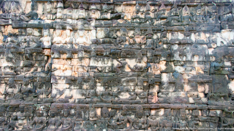 Long wall crowded with small standing relief figures at Angkor Thom.