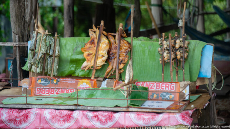 Grilled skewers displayed on banana leaves at a roadside stall at Angkor Thom.
