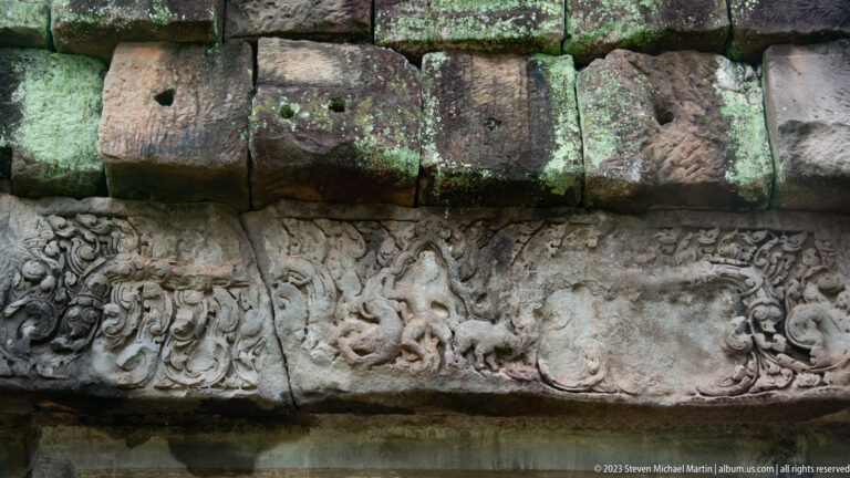 Horizontal sandstone relief band with small animals and scrolling forms at Angkor Thom.