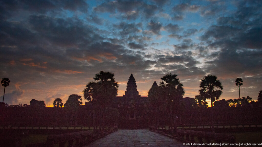 Angkor Wat towers in dark silhouette beneath a dramatic blue, orange, and violet dawn sky at Angkor Wat.