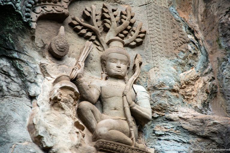 Seated sacred figure with a many-branched or multi-headed form behind the head at Angkor Wat.