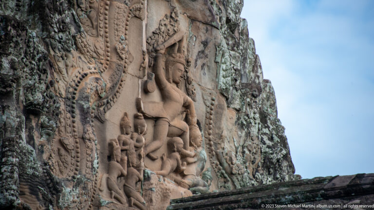 Oblique exterior relief of a large standing or seated deity with attendant figures at Angkor Wat.