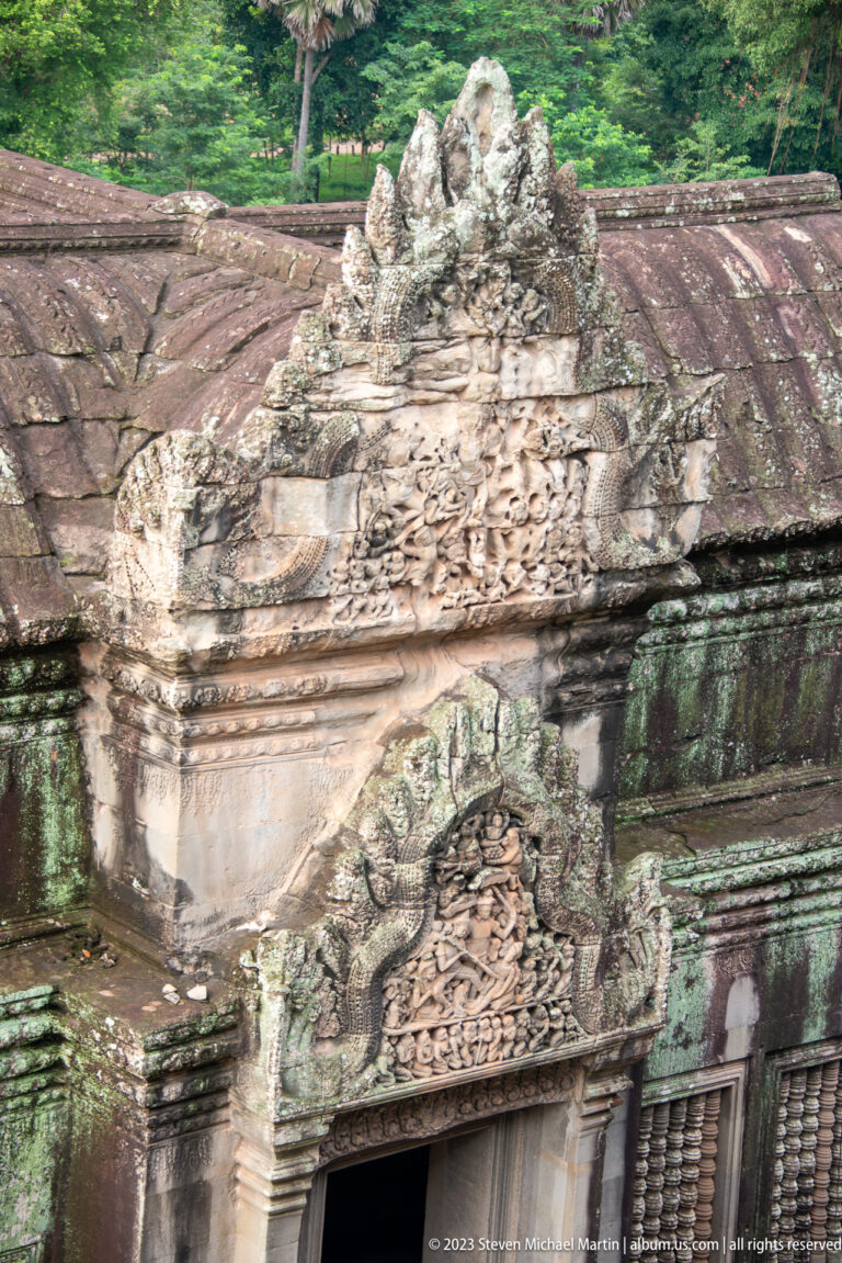 Carved lintel and pediment above a doorway with green-black weathering at Angkor Wat.