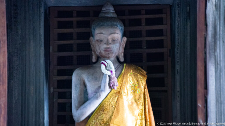 Closer frontal view of the same gold-draped standing Buddha at Angkor Wat.