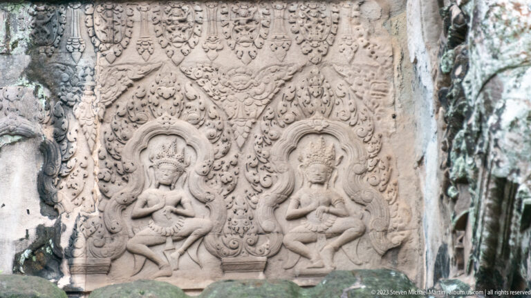 Two small seated sacred figures carved inside circular or arched frames at Angkor Wat.