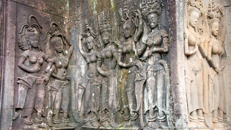 Group of standing devatas carved together in a deep wall panel at Angkor Wat.